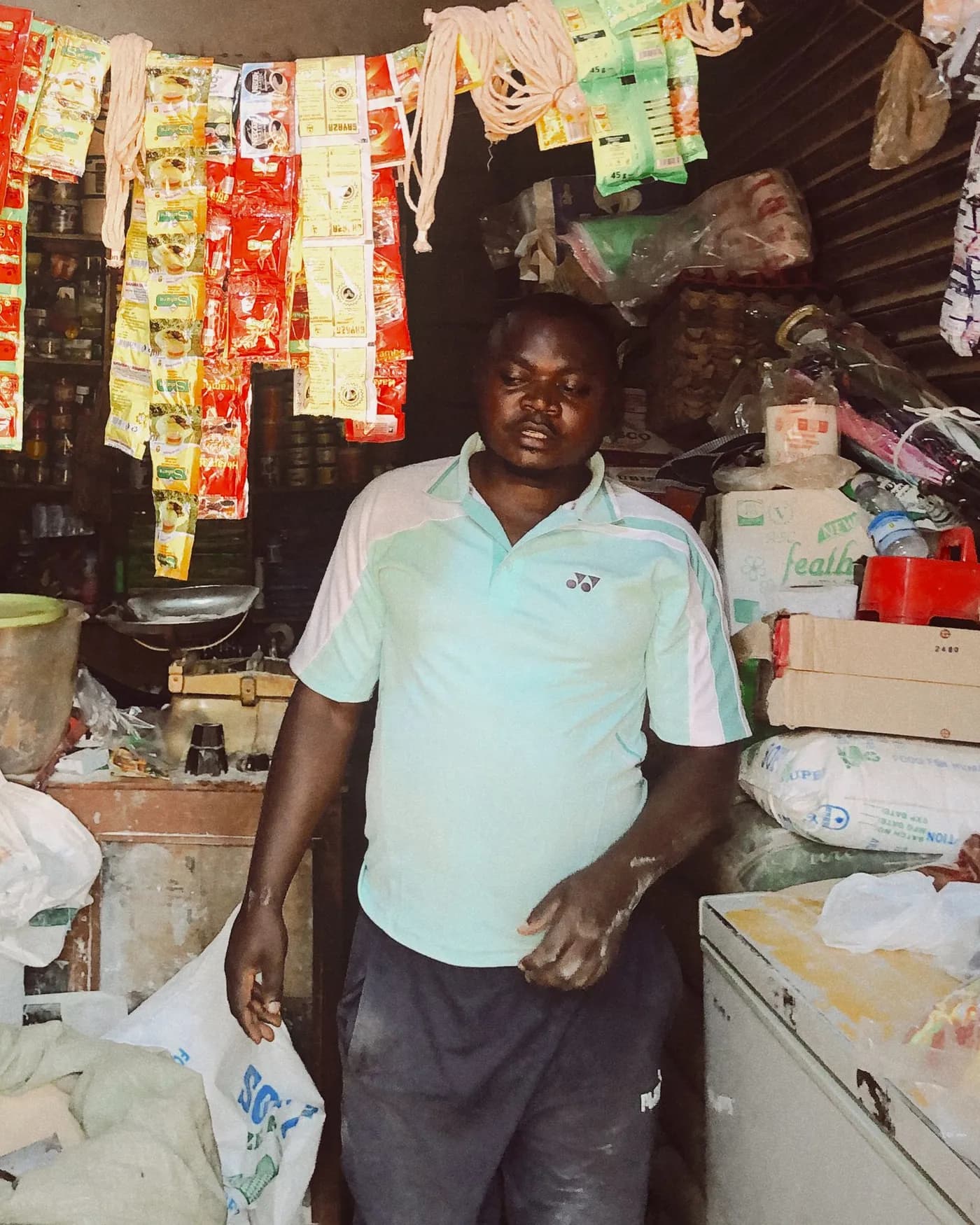 Commerçant debout dans sa boutique de quartier, entouré de ses marchandises